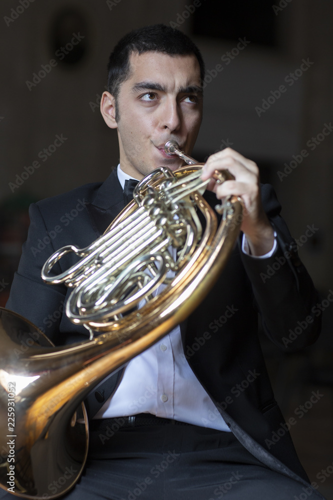 Obraz premium French horn player. Hornist playing brass orchestra music instrument.