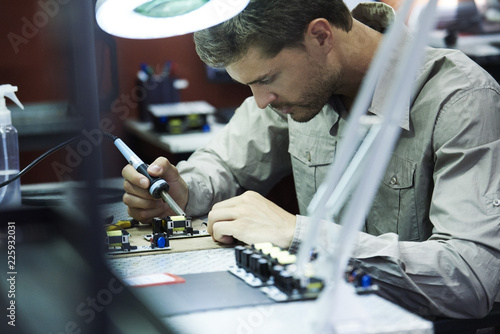 Engineer soldering circuit board in office photo