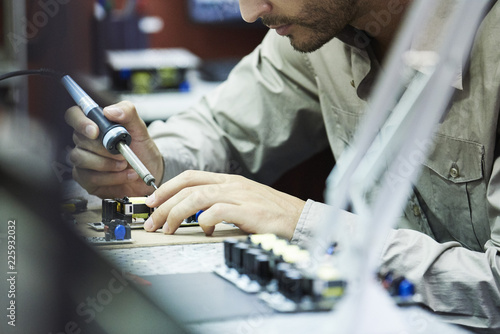 Engineer soldering circuit board in office photo