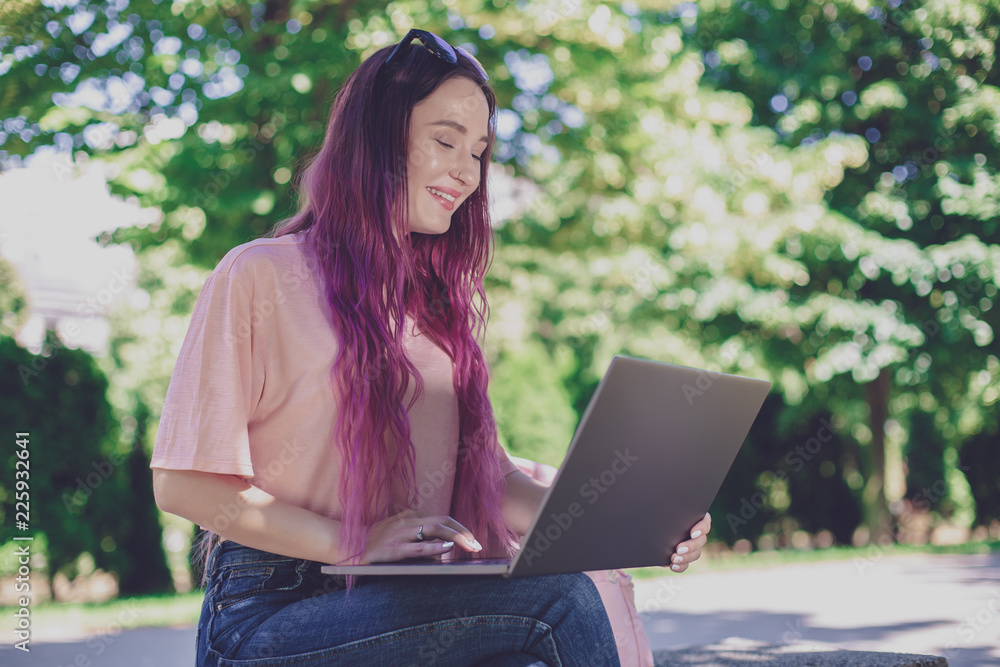 Young girl is studying in the spring park, sitting on the wooden Young girl is studying in the spring park, sitting on the wooden