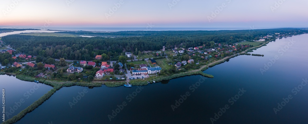 Beautiful sunset over estuary of Vistula river in Gdansk. Summer sunset over sea and river and small village. - obrazy, fototapety, plakaty 