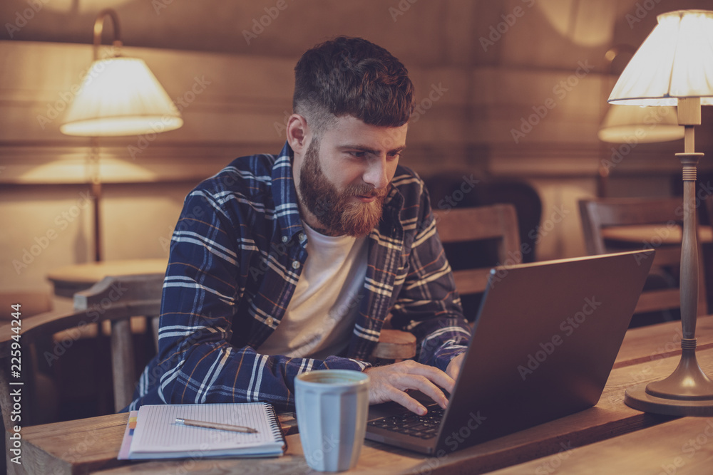 Young professional surfing the Internet on his laptop in a cafe Young professional surfing the Internet on his laptop in a cafe