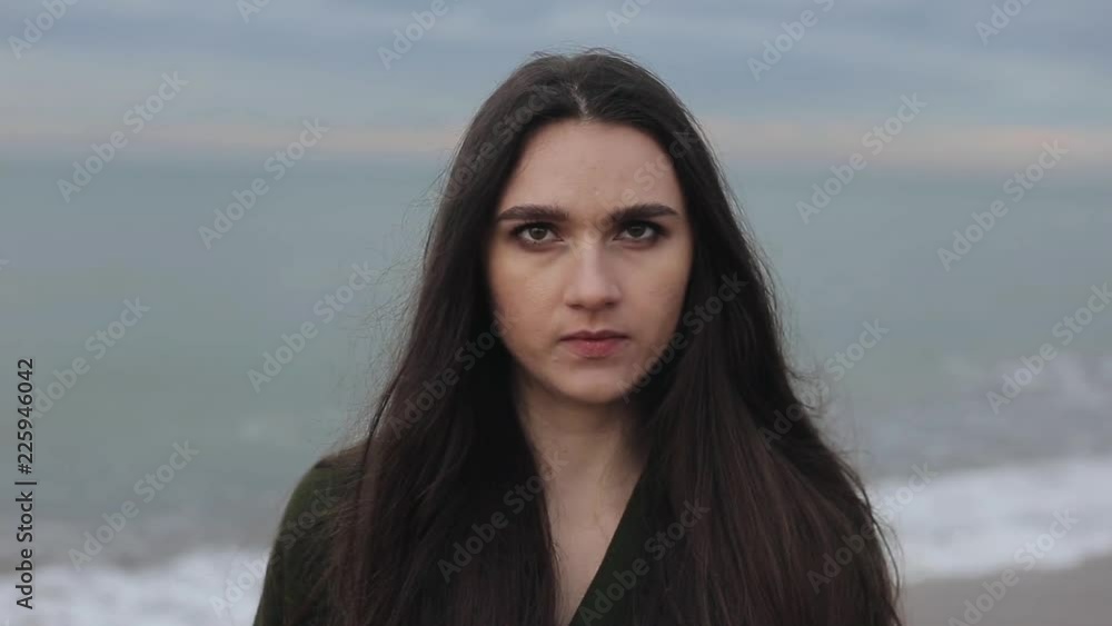 A close view of a seductive young brunette with long loose hair at the seaside in spring A close view of a seductive young brunette with long loose hair at the seaside in spring