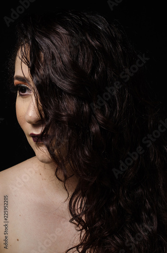 Curly hair girl of dark color and makeup with dark tones.