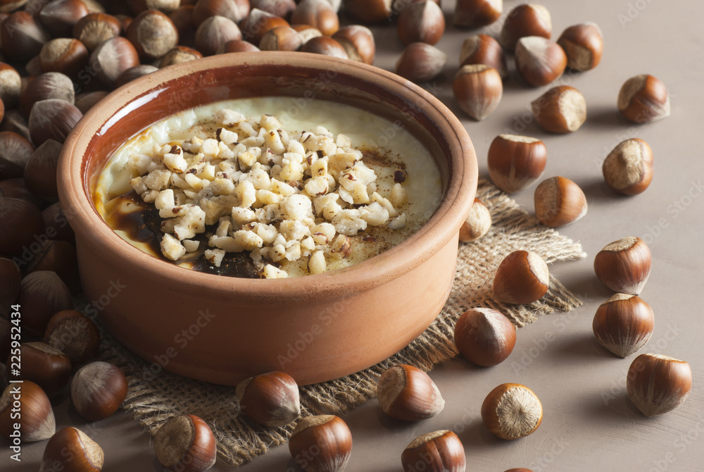 Baked rice pudding turkish milky dessert sutlac in earthenware casserole with hazelnuts Baked rice pudding turkish milky dessert sutlac in earthenware casserole with hazelnuts