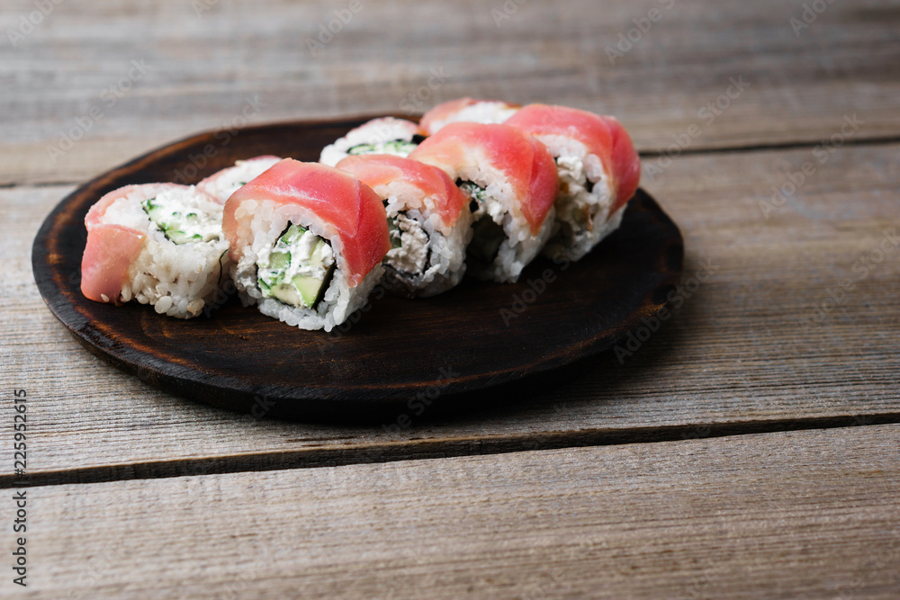 Delicious sushi roll with avocado and cream cheese, covered with tuna slices. Tasty traditional meals, japanese culture, restaurant serving Delicious sushi roll with avocado and cream cheese, covered with tuna slices. Tasty traditional meals, japanese culture, restaurant serving