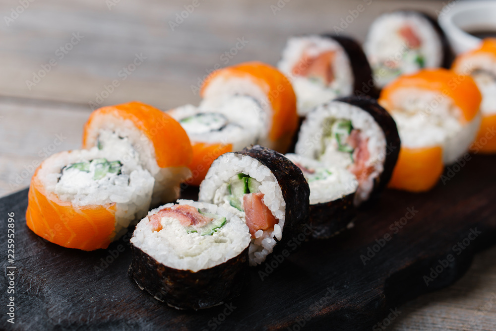 Restaurant menu, Japanese traditional food. Appetizing sushi rolls served on wooden tray Restaurant menu, Japanese traditional food. Appetizing sushi rolls served on wooden tray