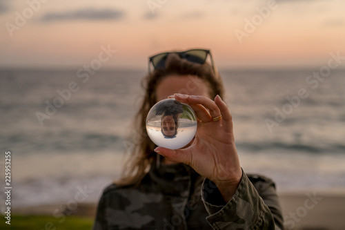 Girl holding a lens ball on the beach at sunset time