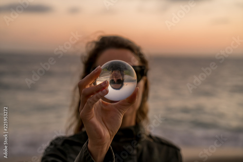 Girl holding a lens ball on the beach at sunset time