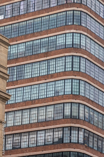 Wallpaper Mural A tall building with many window. The viewer is looking at the corn of the building. A red brick facade is below the windows. A white brick facade is above the windows. This is a vertical picture. Torontodigital.ca