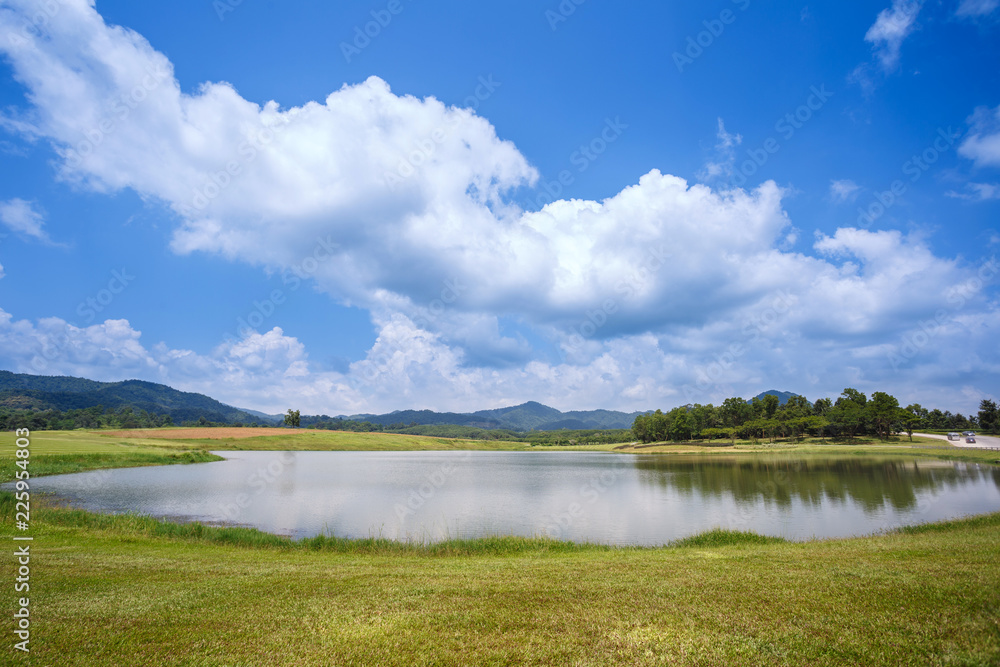 Grass field and small lake with cloudy and blue sky over at Singha Park, Chiangrai, Thailand