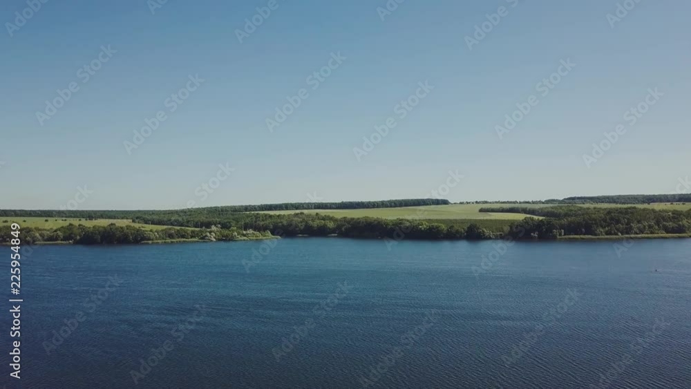 river with waves on the background of the shore with trees and a field on a summer day river with waves on the background of the shore with trees and a field on a summer day