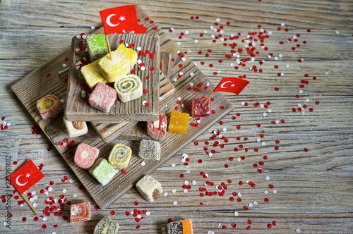 various national Oriental sweets, with paper flags of Turkey, Turkish delight on a wooden white brushed stand and on a white brushed background, horizontal, 