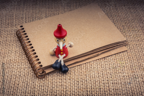 Wooden Pinocchio doll sitti...