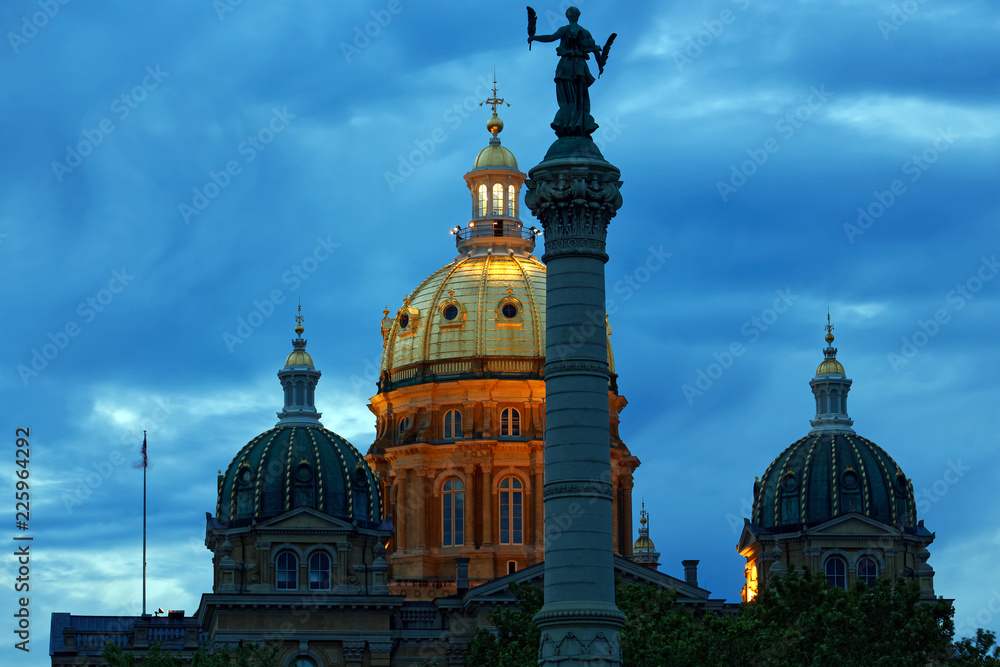 The Iowa State Capitol dome is illuminated behind the Soldiers and Sailors Monument. The Capitol building was completed in 1886 and the Monument was completed in 1896.