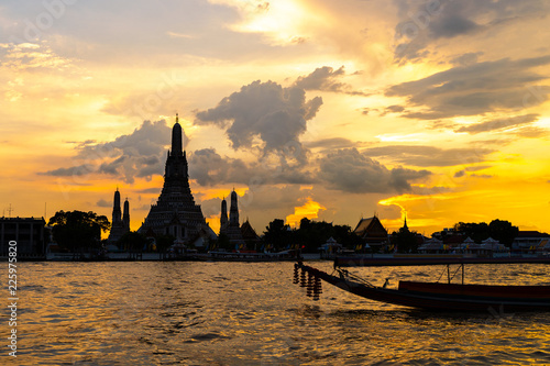 Silhouette of Wat Arun Temple and Boat Beside Chao Phraya River with Beautiful Sunset Through the Cloud, Bangkok, Thailand. One of the Most Famous Place of Thailand's Landmarks. © Opman