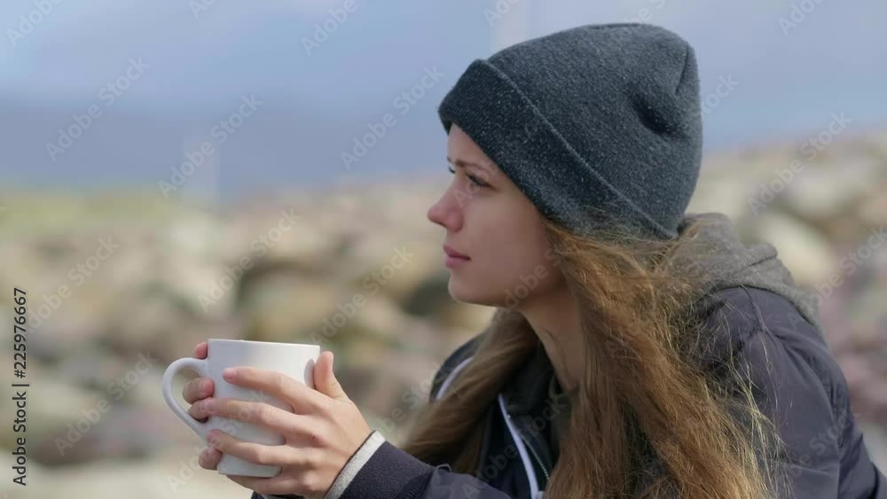 Girls looks over the ocean and drinks a cup of coffee Girls looks over the ocean and drinks a cup of coffee