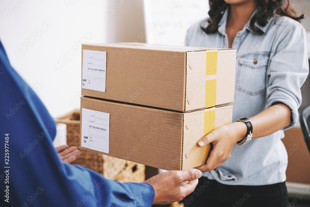 Female delivery service manager giving packages to courier Female delivery service manager giving packages to courier