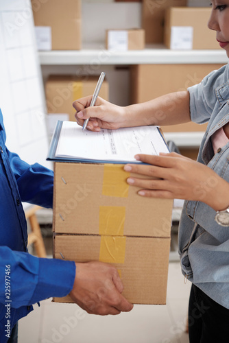 Delivery service manager signing document and taking parcels from courier