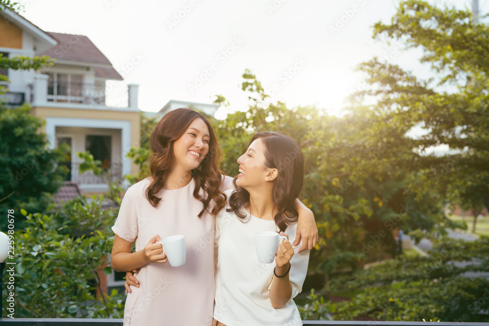 Two Women Relaxing On Rooftop Garden Drinking Coffee Two Women Relaxing On Rooftop Garden Drinking Coffee