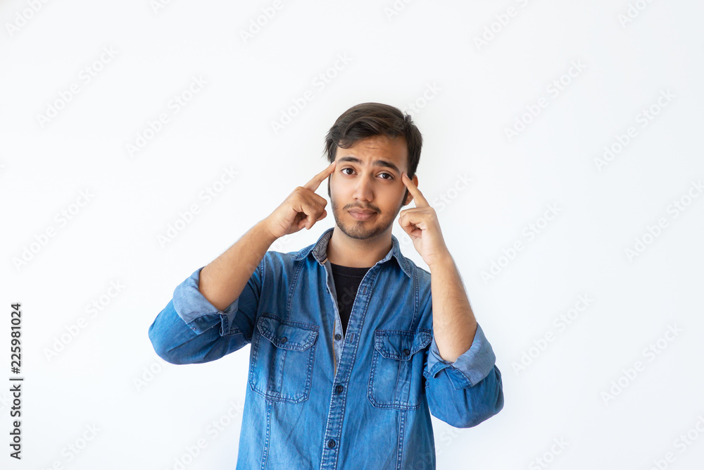 Confident young Indian man touching temples with fingers and looking at camera. Portrait of serious handsome dark haired man asking to think before doing. Need to think concept.