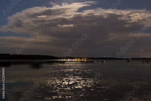 Clouds and stars above lake in the summer night before thunder