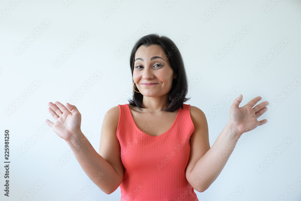 Ironic attractive Caucasian woman shrugging shoulders and spreading hands with palms up. Portrait of pretty middle aged woman in pink dress gesturing and smiling at camera. Do not know concept. Ironic attractive Caucasian woman shrugging shoulders and spreading hands with palms up. Portrait of pretty middle aged woman in pink dress gesturing and smiling at camera. Do not know concept.