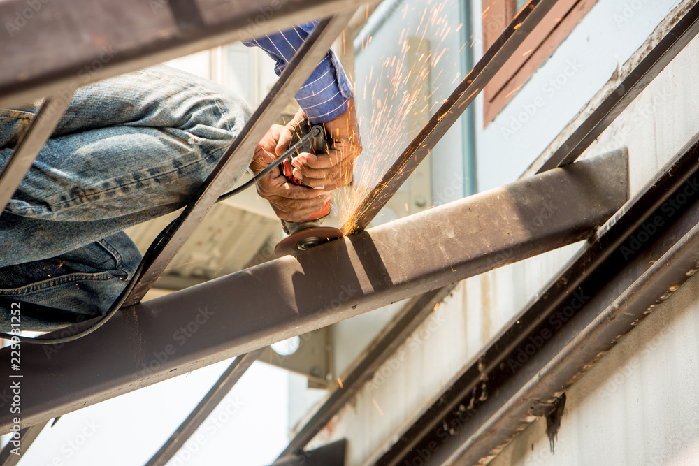 Labour man use electric wheel grinding on steel structure in construction site Labour man use electric wheel grinding on steel structure in construction site