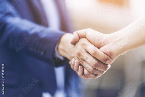 Concept of Negotiating business and handshake Gesturing People Connection Deal. close up hand of business man shaking hands with partner or customer on modern city background,fair play. film tone