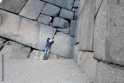 Little boy leaning against a historic castle wall made of huge stone  blocks