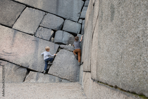 Two boys climbing a historic defence wall made of huge rocks