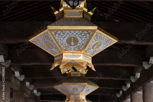 Golden lantern hanging from a roof of an old wooden japanese temple