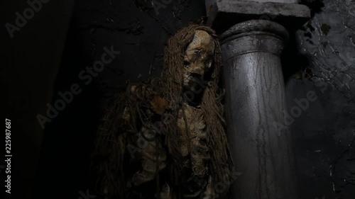 Haunted dead rotting mummy corpse leaning on pillar