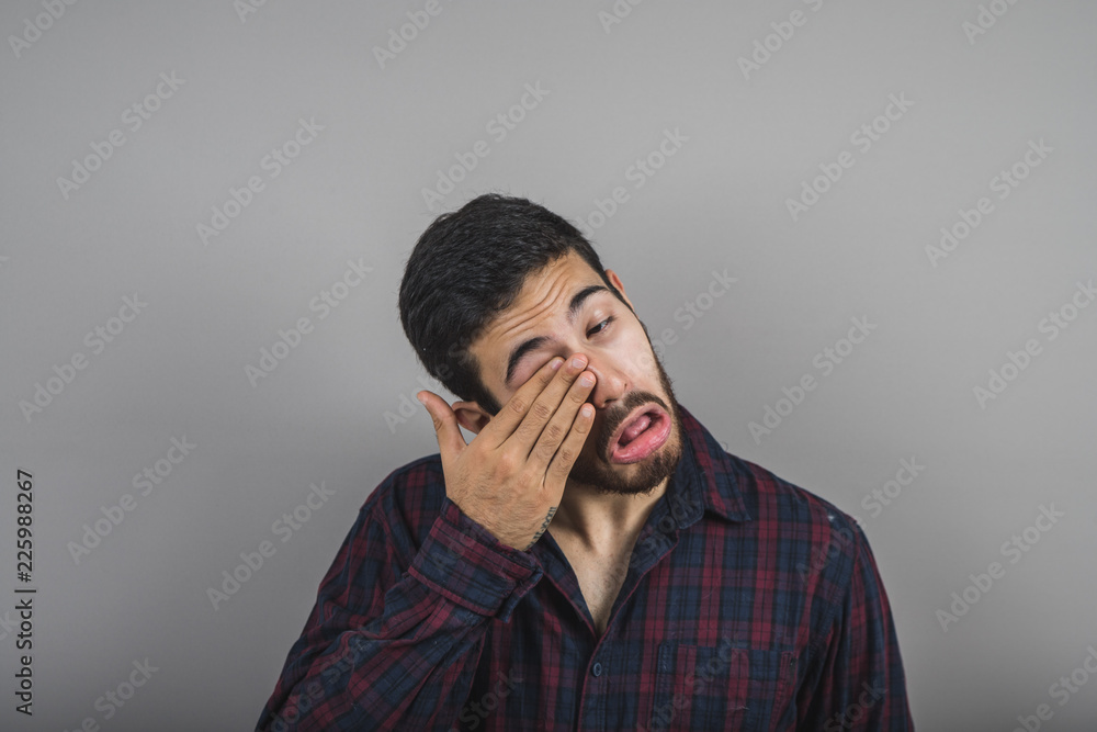 young man scratching his eye, the man is bothered by the eye young man scratching his eye, the man is bothered by the eye