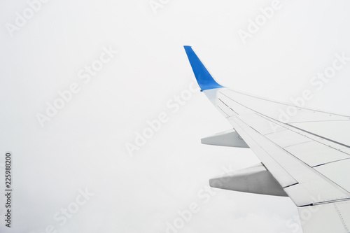 View on airplane wing in the cloudy sky during the flight. Overcast consept, bad visibility.