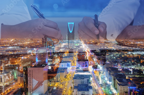 Businessmen hands signing documents on Riyadh skyline city scape background photo