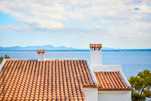 Old ceramic tile roof with seascape in background, Mallorca, Spain.