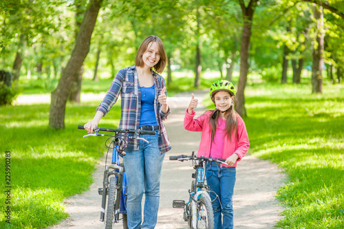 happy mom with her daughter on bicycles show thumbs up