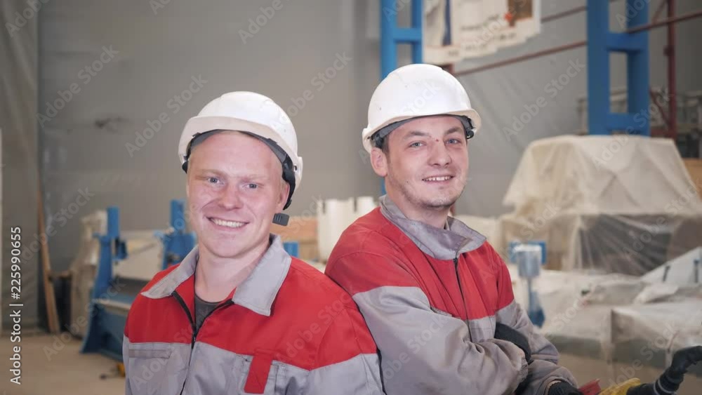 Portrait Workers working with a crane in the warehouse. Smiling Looking at camera. the production of ventilation and gutters. Tool and bending equipment for sheet metal. Portrait Workers working with a crane in the warehouse. Smiling Looking at camera. the production of ventilation and gutters. Tool and bending equipment for sheet metal.
