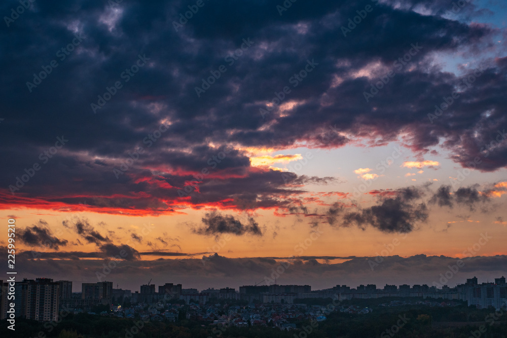 Dramatic colorful autumn clouds at sky over city at sunset, beautiful nature landscape panorama