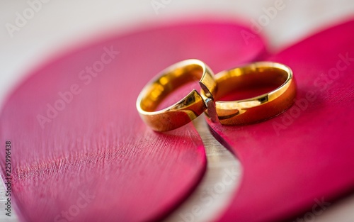 Two broken golden wedding rings on broken red heart