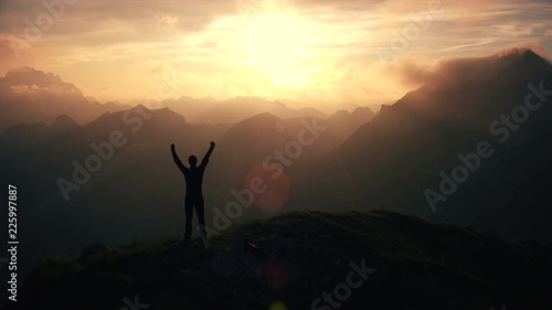 Aerial, edited - Triumphant hiker standing on top of the mountain raising arms photo