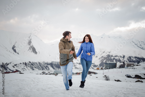 Young and happy lovers on the winter vacations spending time in mountains