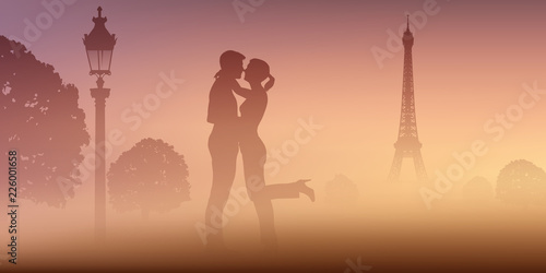 A Paris, un un couple d'amoureux au Champ de mars, s'embrassent devant la Tour Eiffel par un matin de brume