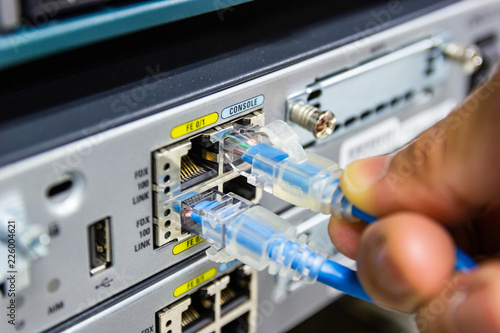 Closeup hand man connection red cable network connection to Network switch in rack, network cables connect SFP module port in the Datacenter room, concept Communication technology