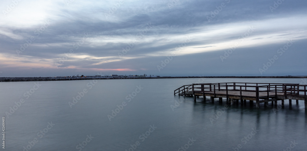 Long exposure of wooden pier at sunrise with lake