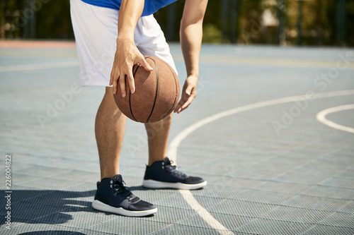 young asian male basketball player practicing dribbling