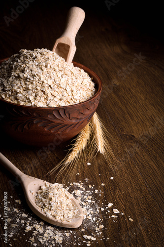 Dry flakes in a wooden bowl on a wooden background near the ears of wheat. wooden spoon with Dry flakes