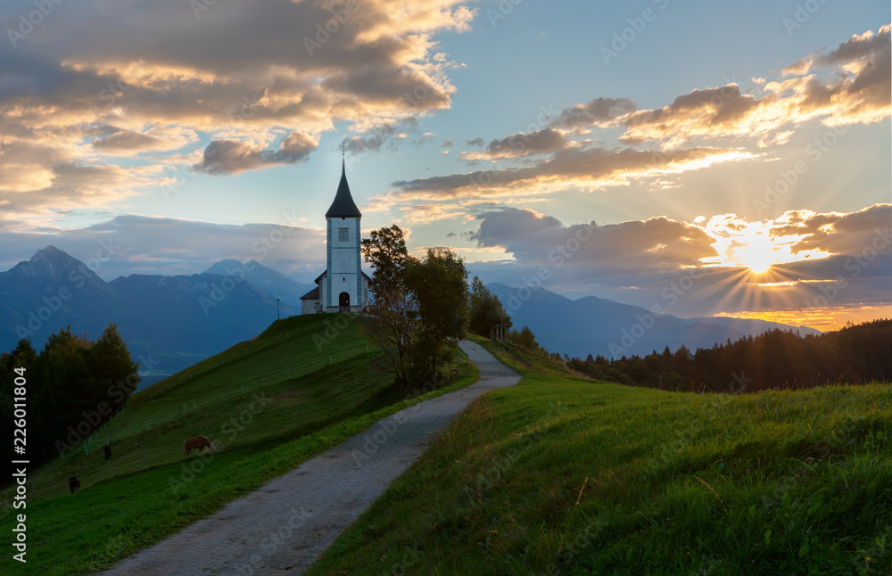 Church on the hill at sunrise. Beautiful scenery at Jamnik, Slovenia. Panoramic view of the Alps behind the church. Church on the hill at sunrise. Beautiful scenery at Jamnik, Slovenia. Panoramic view of the Alps behind the church.