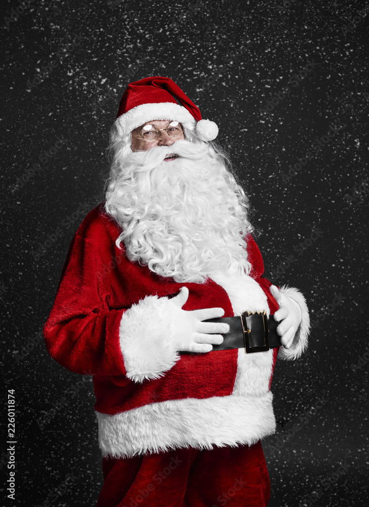 Cheerful santa claus touching his belly among snow falling Cheerful santa claus touching his belly among snow falling